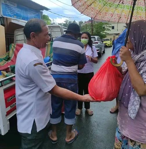 Kepsek SMP Negeri 3 Manado, Rahman Manggopa, S.Pd, M.Pd saat menyerahkan bantuan kepada orangtua siswa korban banjir.