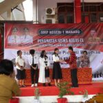 Kepsek SMPN 1 Manado saat menyerahkan Sertifikat Peringkat 1 Niai Ujian Tingkat Satuan Pendidikan TP 2022.2023 dan Sertifikat Peringkat 1 Nilai Akhir TP 2022.2023 kepada Clarissa FT Tumimomor siswi kelas 9.1