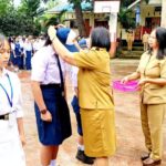 Penyematan tanda peserta MPLS dan penyerahan atribut seragam kepada siswa oleh kepsek SMP Negeri 7 Manado Syenny Waworuntu, S.Pd