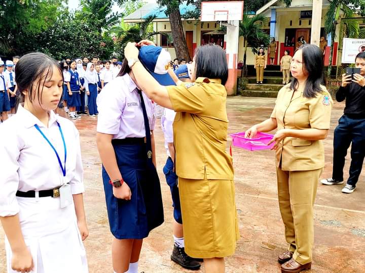 SMPN 7 Manado Penyematan tanda peserta MPLS dan penyerahan atribut seragam kepada siswa oleh kepsek SMP Negeri 7 Manado Syenny Waworuntu, S.Pd